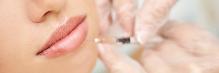 Lip injection at spa salon. Doctor hands. Closeup view. Pretty female patient. Beauty treatment....