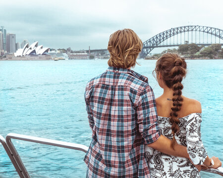 Man and woman standing on oat looking at body of water