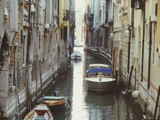 Naklejka na ściany i meble Boats Moored In Canal Amidst Buildings In City