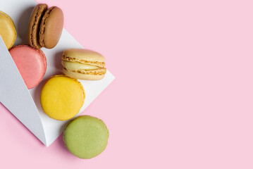 Colorful macarons like a gift on pink background with copy space