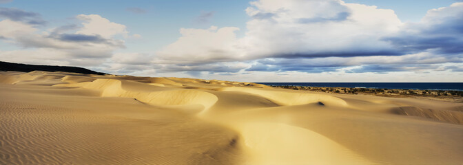 Panorama of large sand dunes rolling down to the coast meeting the Coral Sea and dramatic clouds in the sky on Fraser Island - Queensland