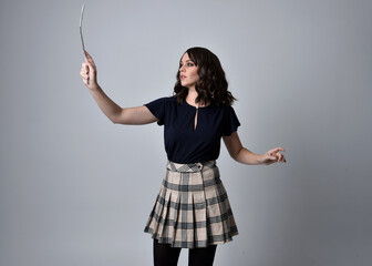 full length portrait of pretty brunette woman wearing tartan skirt and boots with long black...