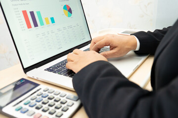 Asian accountant working and analyzing financial reports project accounting with chart graph and calculator in modern office, finance and business concept.