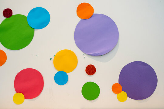 Colorful paper circles on a white background, children's arts and crafts, kids classroom wall. Variation. Stock Photo.