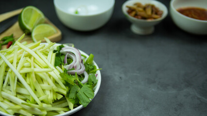 Yum, mango photo top views Food arrangement. Spicy salad food, topped with fried nuts and crispy fish. The main ingredients are raw mango, lime juice, fresh chili powder, fish sauce, sugar to mix.