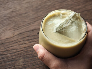hand holding iced green tea on wooden table