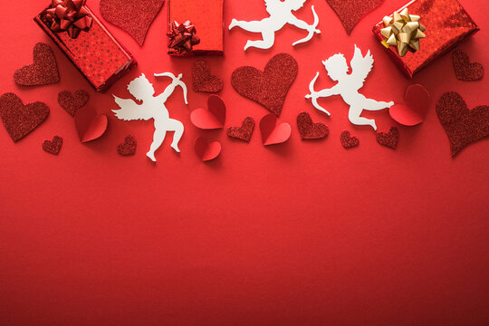 Flying cupid silhouette with hearts, gifts, happy Valentine's Day banners, paper art style. Amour on red paper