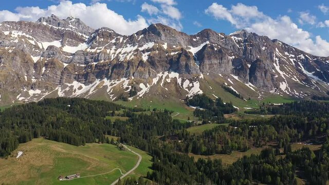 Aerail footage of the S&auml;ntis mountain range landscape and schw&auml;galp pass in Canton Appenzell in Switzerland on a sunny spring day. Shot with a backward motion