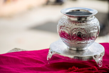Beautiful carved silver pot or kalash and stand used in hindu rituals, on blur background.