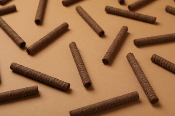 Flat lay with chocolate wafer rolls on brown background