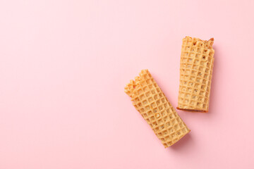 Tasty wafer rolls with condensed milk on pink background