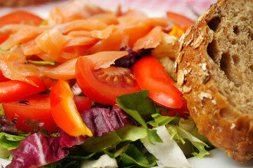 Fresh salad with smoked salmon pieces, lettuce, tomato, salad pepper and olive oil, Close up, selective focus