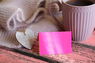 Partial blurred cozy  still life with cup of coffee  warm scarf and  empty card, copy space, Sunrise morning light and shadows. At home.  love concept.