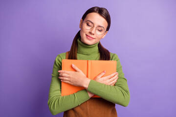 Portrait of pretty dreamy cheery girl embracing holding book diary isolated over bright violet color background