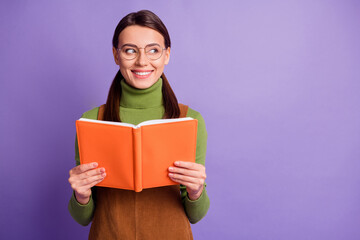 Obraz premium Portrait of lovely brainy cheery girl reading book looking aside ad solution isolated over pastel violet color background