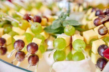 Smorgasbord. Canapes with cheese, bacon, green and red grapes on the glass plate. Close-up, selective focus