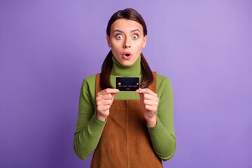 Portrait of lovely amazed funky girl holding in hands bank card staring eyes isolated over bright...