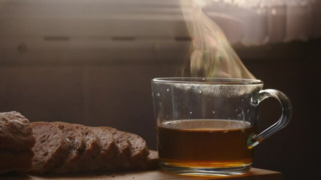 Hot steaming tea cup and sliced bread on table. Preparing breakfast meal in caravan rv interior. Holiday trip in motor home. Camper car vacation travel. Slow motion.