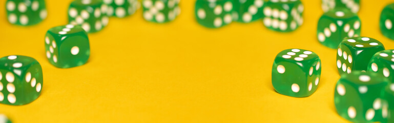 A group of green dice lies on a yellow background, selective focus, place for text, business or casino banner