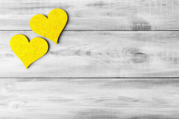 Two yellow Valentine’s hearts over grey wooden background