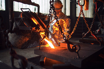 Molten metal being poured into molds in foundry.