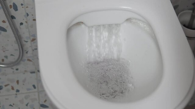 Close up of a water with paper flushing down into the toilet bowl in bathroom. Stylish modern toilet