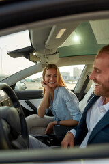 Cheerful young caucasian spouses sitting on car front seats
