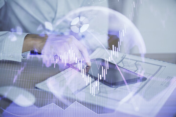 Double exposure of man's hands holding and using a digital device and forex graph drawing. Financial market concept.