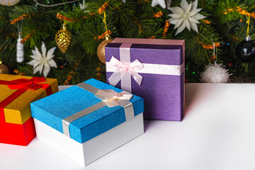 Gift boxes with ribbons with a Christmas tree in the background