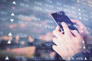 Double exposure of man's hands holding and using a digital device and forex graph drawing. Financial market concept.