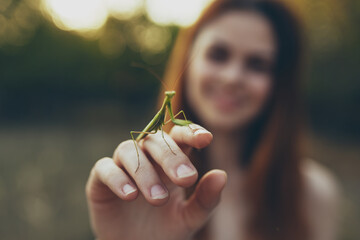 romantic woman with praying mantis on her hand outdoors in the meadow - obrazy, fototapety, plakaty