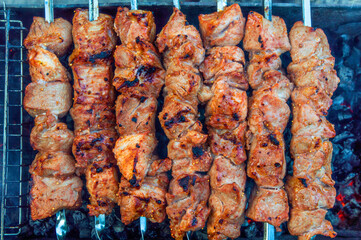 skewered pork kebab grilled over charcoal, smoke over a barbecue, medium cooking, close