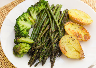 lean dish of cooked fried inflorescences of broccoli, asparagus growth and baked potatoes and Provencal herbs