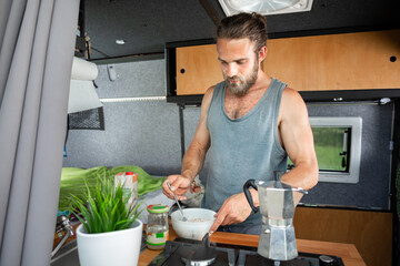 Man preparing cereal inside a camper van