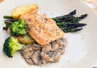 dish of fried river trout fillet with garnish of broccoli, asparagus sprouts and mushroom sauce