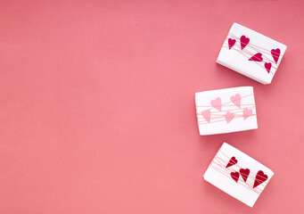 Simple, classic white wrapped gift boxes on pink background with braid and paper hearts with copy space
