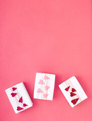 Simple, classic white wrapped gift boxes on pink background with braid and paper hearts with copy space