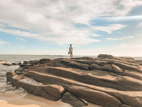 Man standing on rock beside ocean