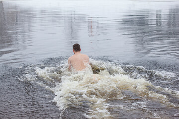 Man entering the icy water of a winter river in water baptism in the Orthodox tradition. Dnieper. Kiev. Ukraine