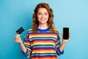 Photo of adorable ginger woman wear colorful sweater holding credit card modern device isolated blue color background