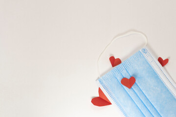 red heart on a mask on valentine's day on a white isolated background. heart surgical mask with place for inscription, mock up, copy space