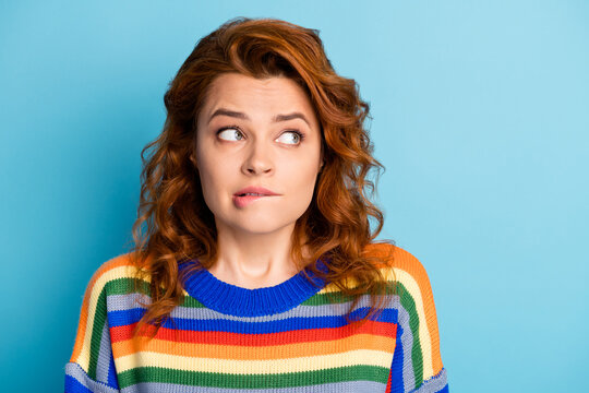 Close up portrait of confused minded lady look empty space bite lip wear pullover isolated on blue color background