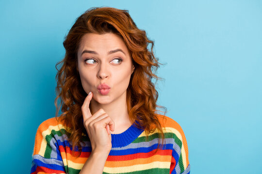 Close up photo of adorable lady look empty space kiss finger on chin wear sweater isolated on blue color background