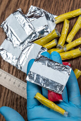 evidence of smuggling traffic: Packaging of a narcotic substance in the hand of a forensic expert against the background of other arrested materials, cocaine, heroin, spice