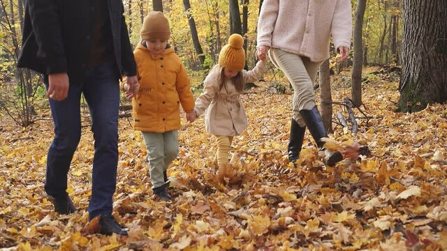Parents and kids walk in the forest on a sunny fall day, posing, smile and laugh