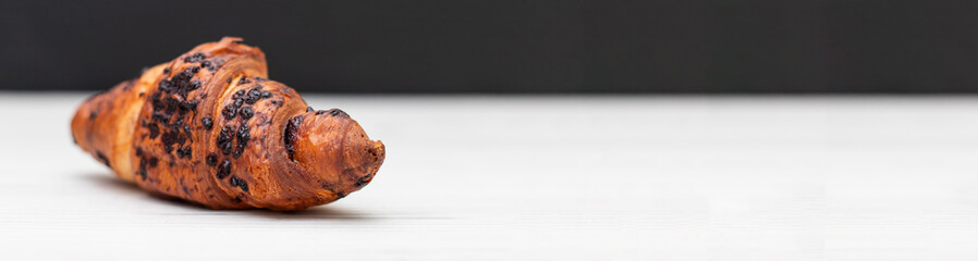 From above of delicious fresh crusty croissant and pieces of dark chocolate composed on a dark background. banner