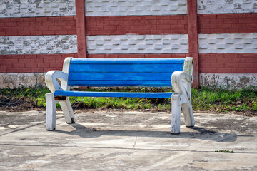 Bright blue colored sitting bench with white handrest on a railway platform.