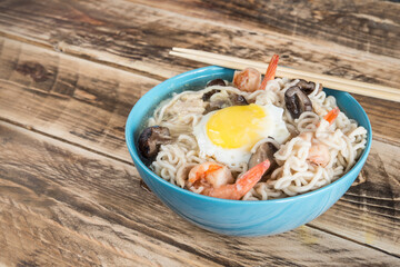 Chinese soup with udon noodles, pork, boiled eggs, mushrooms and prawns close-up in a bowl on the...