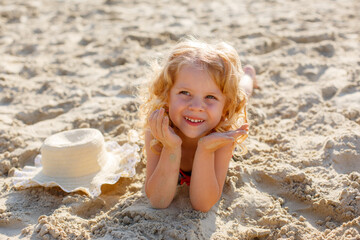 little girl lying on the beach on the sand summer
