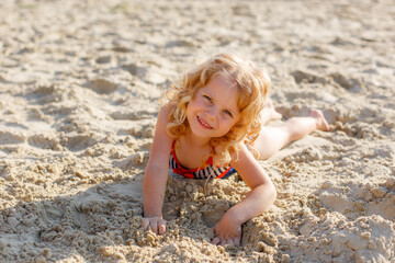 little girl lying on the beach on the sand summer